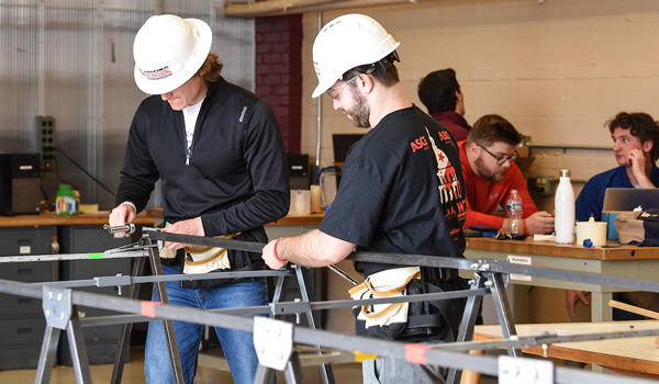 Civil Engineering students with hard hats working on a project. 