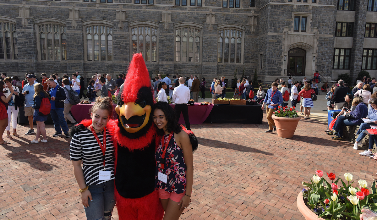prospective students pose for a photo with CUA's mascot, Red the cardinal