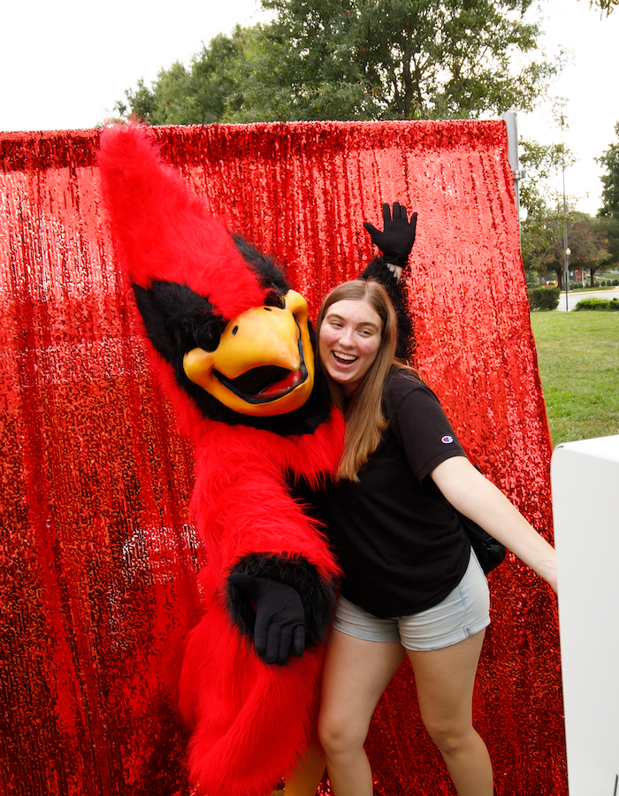Student taking a photo with Red the Cardinal, Catholic University's mascot