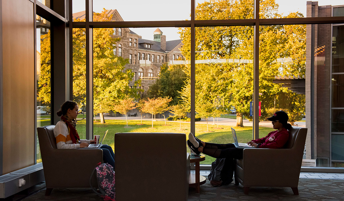 Students sitting in student center with a view of fall colors