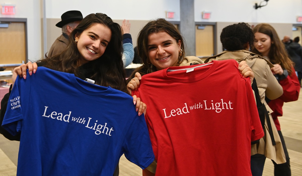 students holding up Lead with Light T shirts
