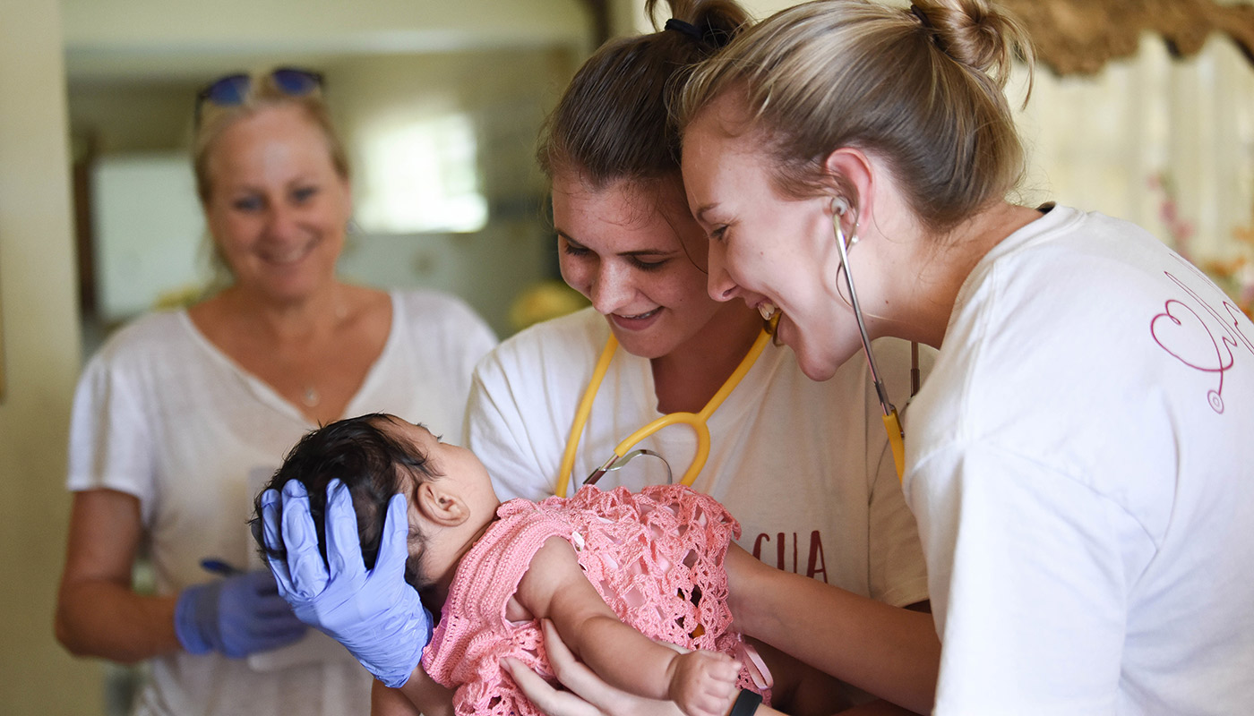 Nursing students holding a baby. 