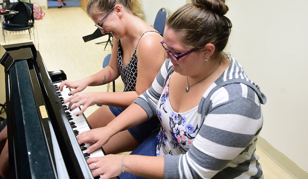 Two students playing the piano together.