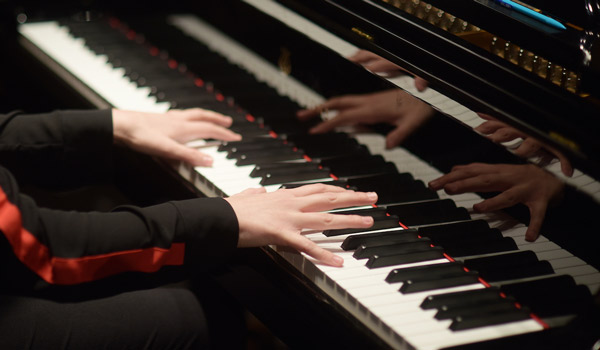 A student practicing a piano on stage.