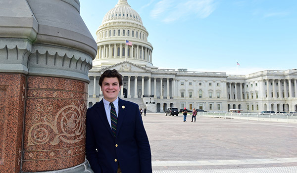 A student standing in front of the U.S. Capitol building at his internship.