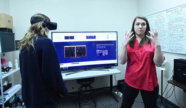 Two students presenting their Psychology research using virtual reality goggles.