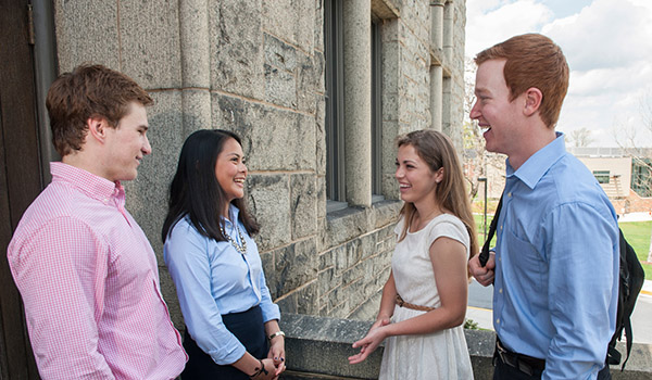 Four students chatting in front of McMahon Hall.