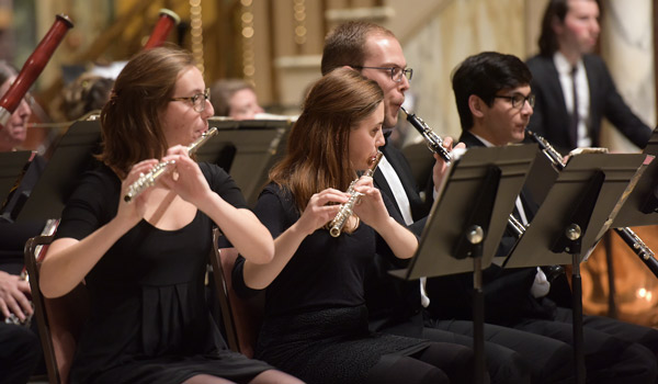 Catholic University woodwind instrument players performing on stage.
