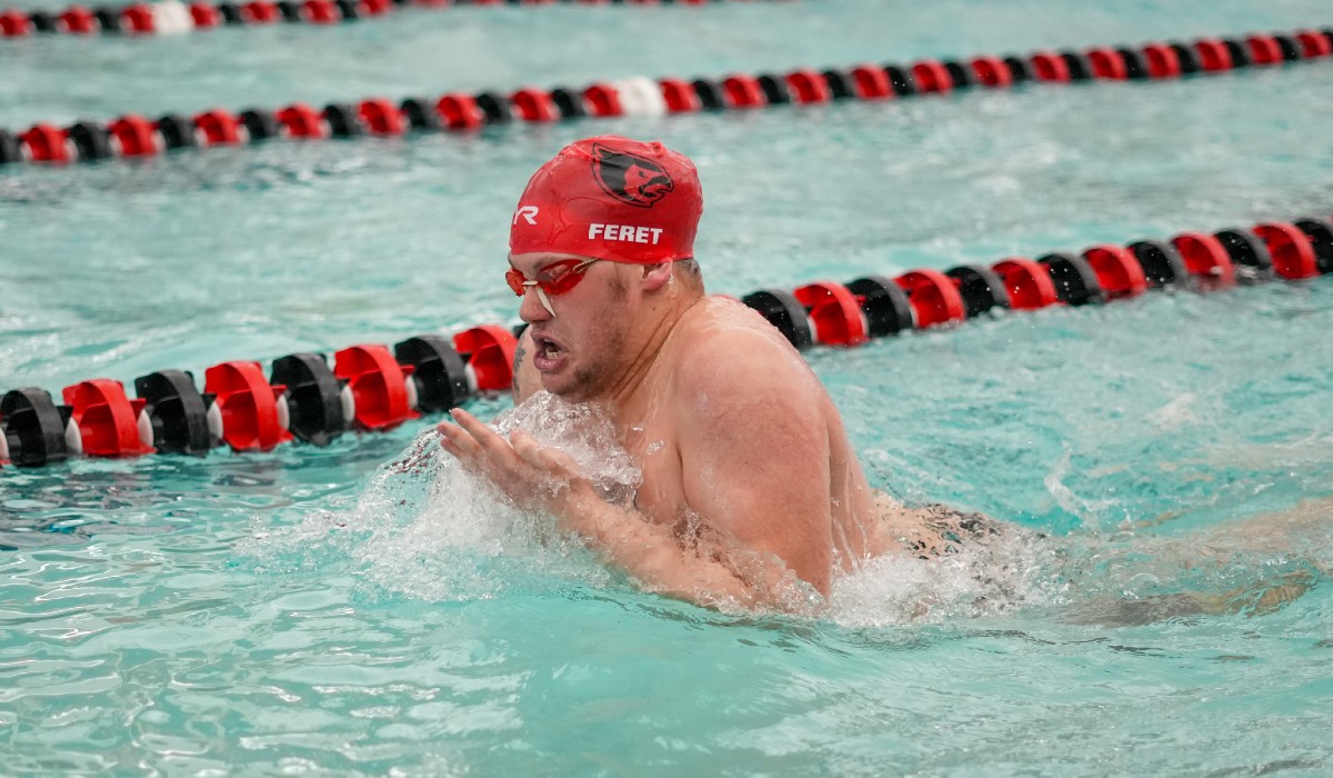 Elijah is swimming in the University pool, completing the breast stroke.