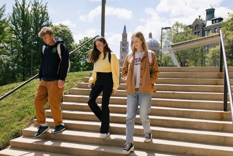 students walking down steps on campus and smiling