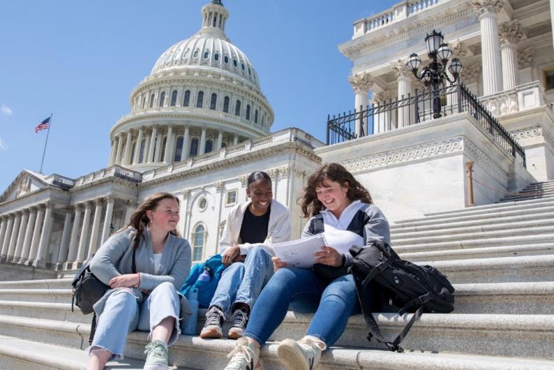 girls sitting on the steps of the U.S. capitol doing school work
