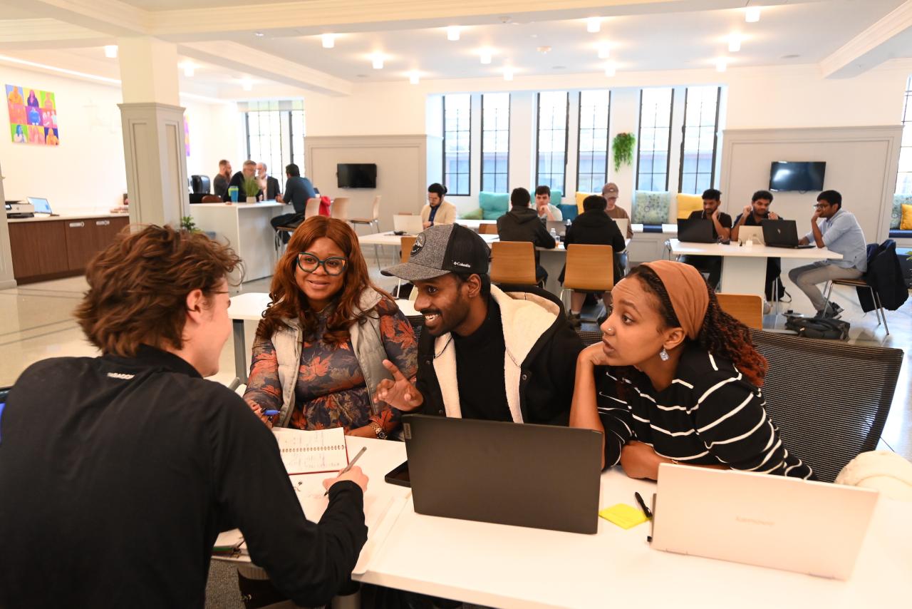 Students gather around laptops at hackathon event