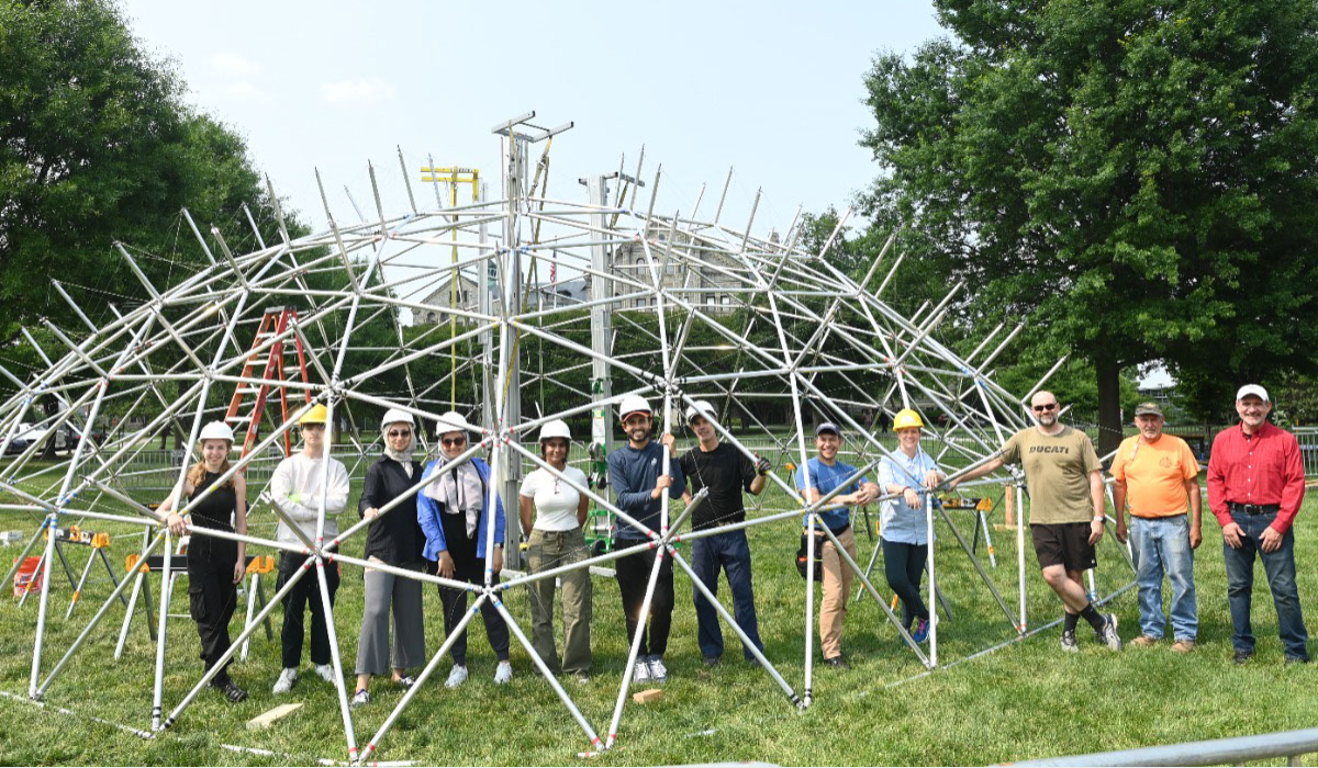 Students stand with the partially reconstructed geodesic dome on campus